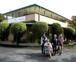 New sign reads 'Waminda' with a artwork of a sand goanna with elders, clients and staff from the hub.